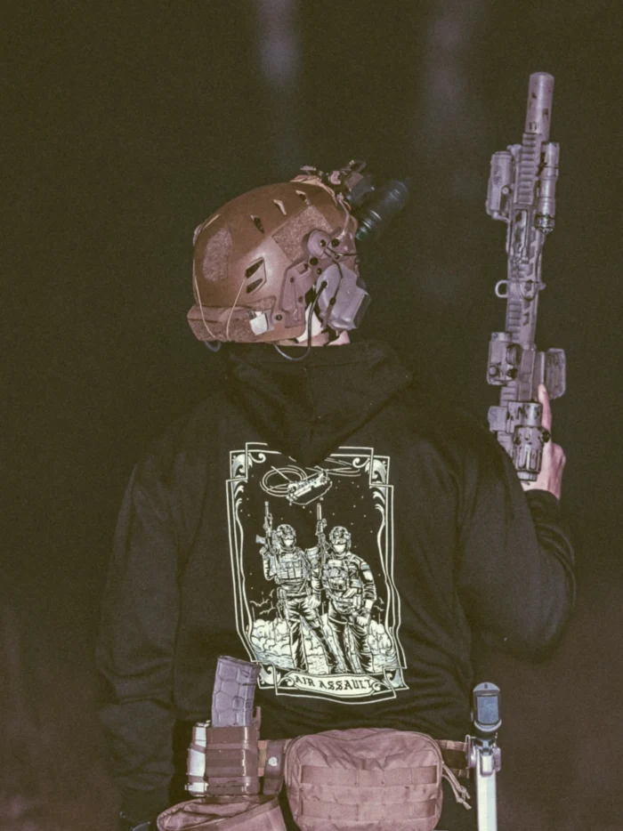 the trace apparel collection featuring 2 air assault operators standing in front of a chinook