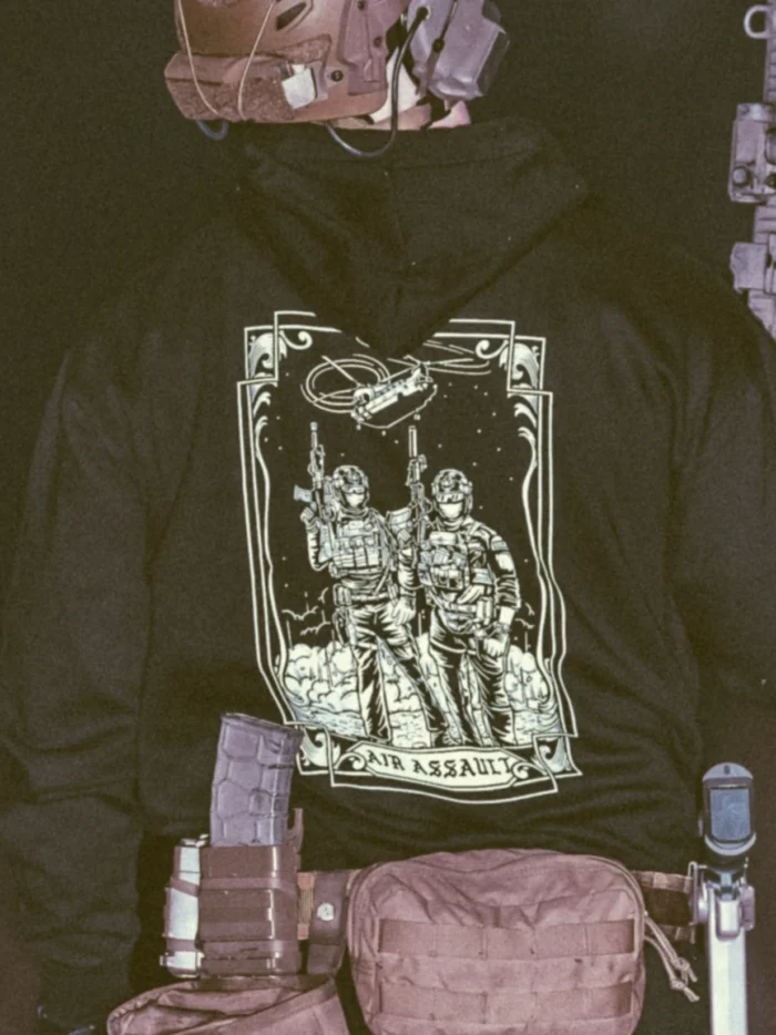 the trace apparel collection featuring 2 air assault operators standing in front of a chinook