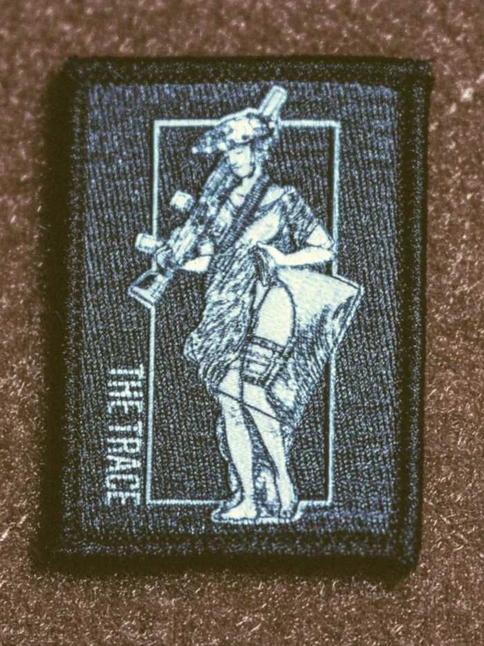 the trace apparel collection patch featuring a woman holding a machine gun