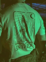 Tactical T-shirt with a skeletal sniper design, positioned on a pile of skulls and holding a high-caliber Arctic Warfare Super Magnum rifle.