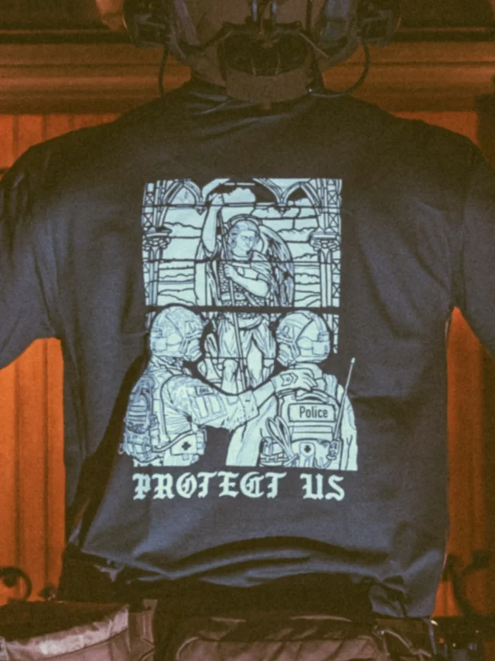 the trace apparel collection featuring a military and a police guy standing in front of a tinted window that displays saint michael the protector